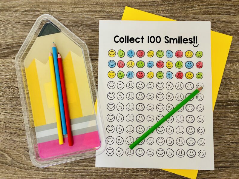 an image of 100 smiley faces on a printable with a few colored in to celebrate the 100th day of school