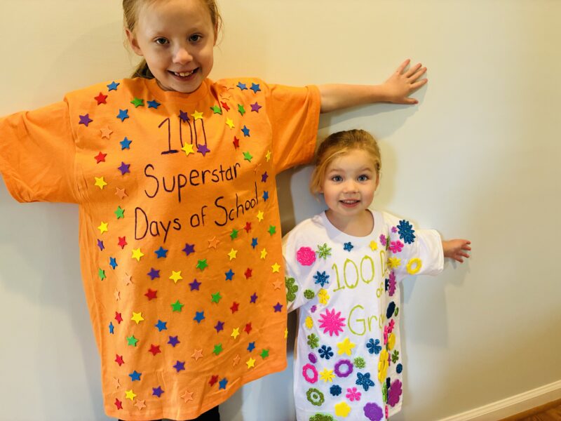 two students showing off shirts they decorated to celebrate the 100 days of school