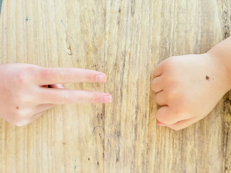 Team Building Activities for Kids an image of two students participating in a game of rock, paper, scissors as a team building activitiy