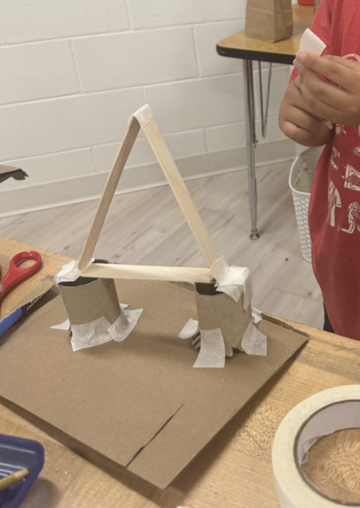 Fifth Grade Science Projects an image of a student using recyclable materials to construct a strong bridge