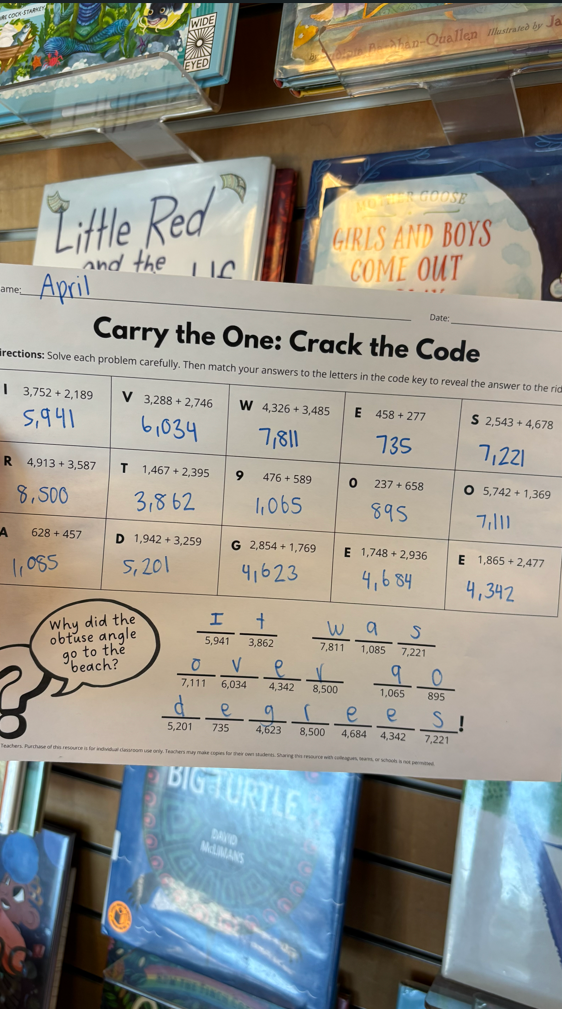 Teacher holding up a completed math joke puzzle in a classroom.