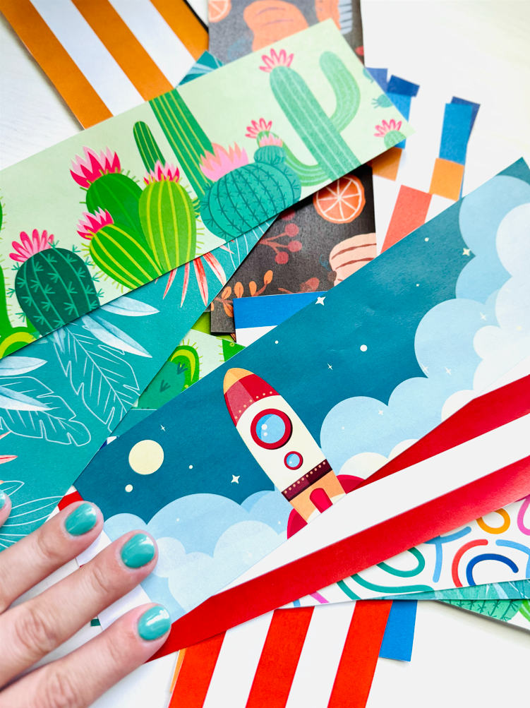 Teachers hand on top of a pile of colorful printable bulletin board borders