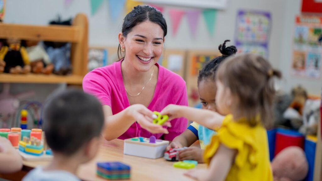 an image of a preschool teacher teaching preschool students at a center table